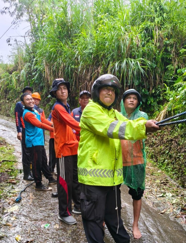 Bhabinkamtibmas Tihingan Bersama BPBD dan Warga Evakuasi Pohon Tumbang.